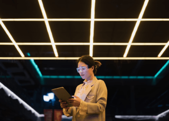 Girl engrossed in mobile phone amidst a futuristic LED-lit maze, symbolizing the intersection of AI ethics and responsible innovation.
