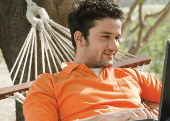 Relaxed guy on a hammock finding work-life balance while using a laptop, illustrating effective tips for balancing work, college, and life.