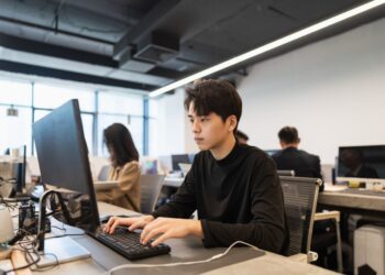 Young male PHP intern in black shirt focused on computer screen during internship. Implementing proven strategies for PHP internship success.