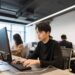 Young male PHP intern in black shirt focused on computer screen during internship. Implementing proven strategies for PHP internship success.