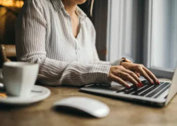 Young woman with laptop applying for editorial assistant position in India after completing English literature degree.